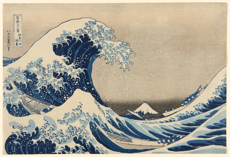 A towering blue wave curls over three boats, with a small snow-capped Mount Fuji in the distance